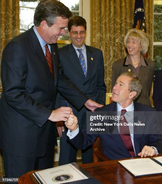 President Bush hands a pen to his brother, Florida Gov. Jeb Bush, as they sign an agreement to provide $7.8 billion over 30 years to help restore the...