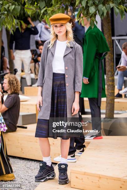 Model, wearing an orange hat, white t-shirt, midi skirt, grey coat and black sneaker, is seen during the 94th Pitti Immagine Uomo at Fortezza Da...