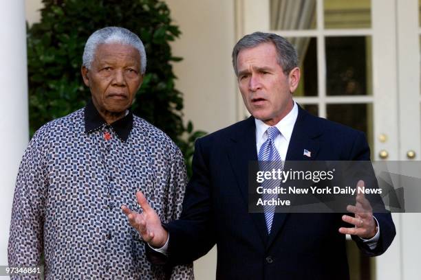 President George W. Bush speaks to the press as Nelson Mandela looks on during a press conference outside the Oval Office after their meeting. They...