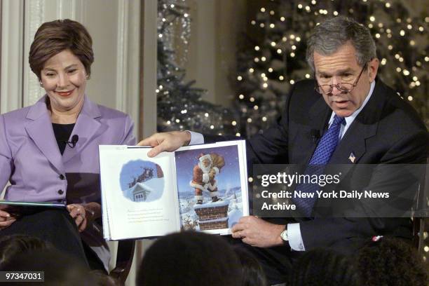 President George W. Bush reads "'Twas the Night Before Christmas" to school children in the East Room of the White House as First Lady Laura Bush...