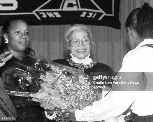 Principal Melanie Johnson [left] stands beside Rosa Parks as she accepts flowers from students at Megnetech JHS 231 in Laurelton, Queens.