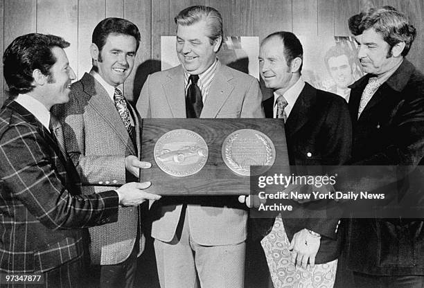 Race drivers Mario Andretti, Al Unser, Perneli Jones and Joe Leonard flank Marty Donahue as they accept award for Indy 500.