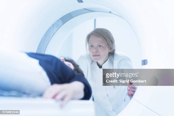 mature woman having ct scan, radiologist standing beside tunnel - sigrid gombert fotografías e imágenes de stock