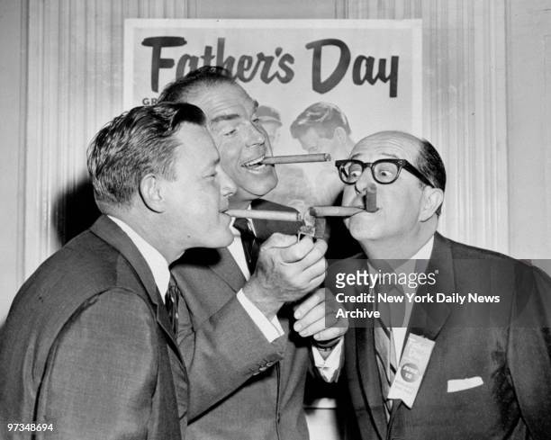 Ralph Houk and Phil Silvers get their cigars lit by Fred MacMurray during the celebration of the Fathers of the Year awards at the Waldorf Astoria....