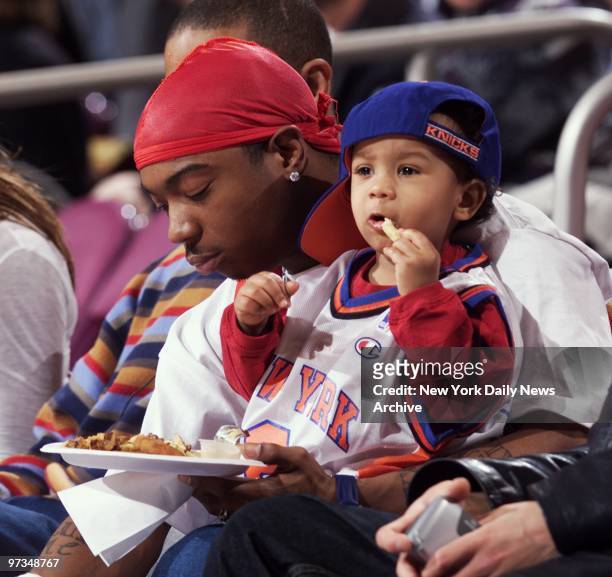 Rap artist Ja Rule and son grab a snack courtside as they take in the action between the New York Knicks and Toronto Raptors at Madison Square Garden.