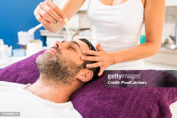 man getting eyebrows waxed - man eye cream stock pictures, royalty-free photos & images