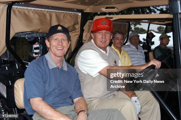 Real-estate mogul Donald Trump and director Ron Howard ride golf cart during the opening celebration for Trump's latest venture, the Trump National...