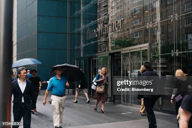 Pedestrians carry umbrellas while passing in front of the Time Warner Center in New York, U.S., on Wednesday, June 13, 2018. AT&T Inc.'s sweeping...