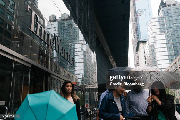 Pedestrians carry umbrellas while passing in front of the Time Warner Center in New York, U.S., on Wednesday, June 13, 2018. AT&T Inc.'s sweeping...