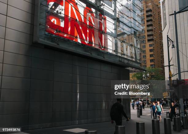Pedestrians pass in front of a building complex displaying Time Warner Inc. Brand CNN television network signage in New York, U.S., on Wednesday,...