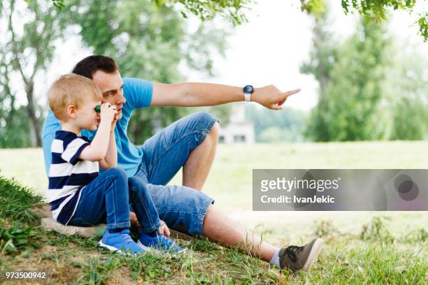 little boy and father playing with binoculars in nature - ivanjekic stock pictures, royalty-free photos & images