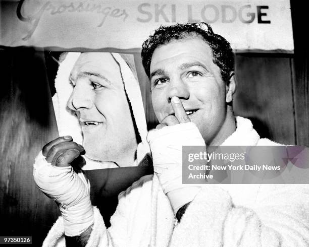 Rocky Marciano looks at picture of himself with split nose he received in fight with Ezzard Charles.