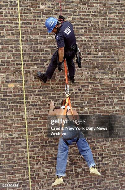 Rescuer lowers construction worker to earth after he was left clinging to rope 12 stories above ground when scaffolding collapsed at building at...