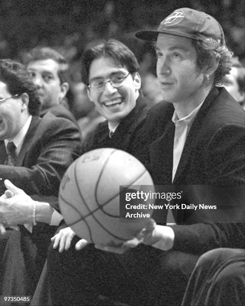 Retired tennis star John McEnroe catches basketball on sidleines at Knicks vs Hawks game.