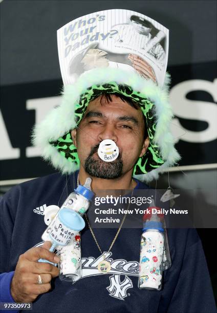 Ricky Velez of Jersey City pokes fun at the Boston Red Sox with a getup that includes a cap festooned with bottles and pacifiers and topped with a...