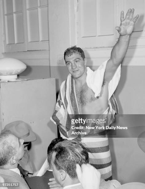 Rock Unchipped. Umarked after his 11-round TKO triumph over Roland LaStarza, Rocky Marciano waves happily in dressing room.