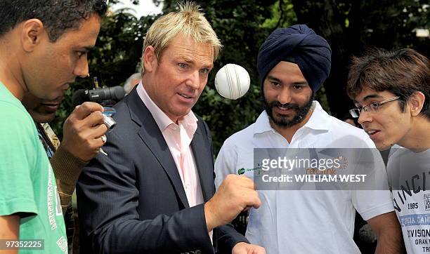 Australian cricketer Shane Warne shows some Indian students his art of spinning the ball during a picnic at Parliament House in Melbourne on March 2,...