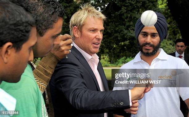 Australian cricketer Shane Warne shows some Indian students his art of spinning the ball during a picnic at Parliament House in Melbourne on March 2,...