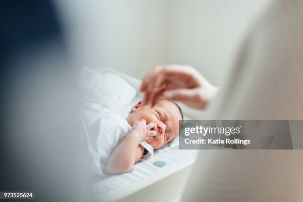 mother and father looking at newborn baby, focus on baby - baby changing mat stock-fotos und bilder