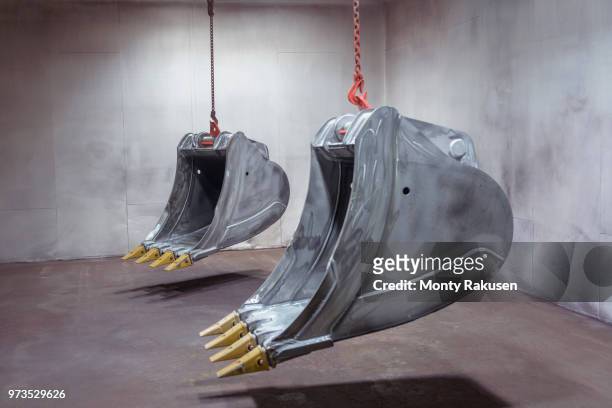 digger buckets hanging in spray booth in engineering factory - monty shadow stockfoto's en -beelden