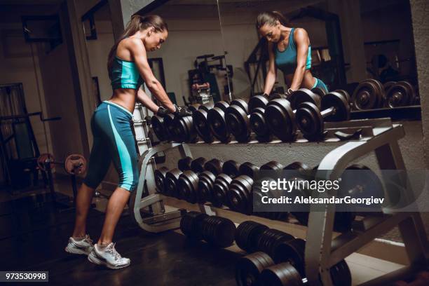 athletic female choosing weights and preparing for training session - inner courage stock pictures, royalty-free photos & images