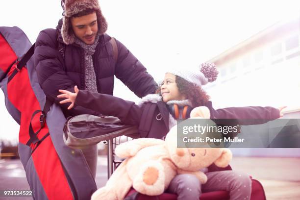 father pushing girl on luggage trolley - luggage trolley stock pictures, royalty-free photos & images