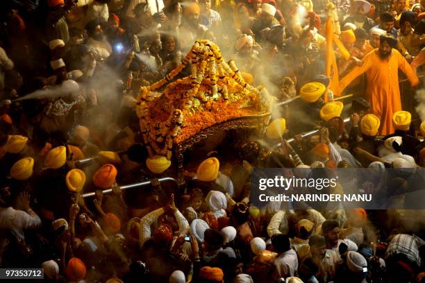 Indian Sikh devotees spray perfume on the Palki Sahib which carries The Guru Garnth Sahib in a procession from the Golden Temple to Sri Akal Takhat...