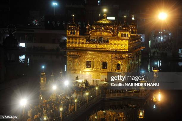 Indian Sikh devotees spray perfume on the Palki Sahib which carries The Guru Garnth Sahib in a procession from the Golden Temple to Sri Akal Takhat...