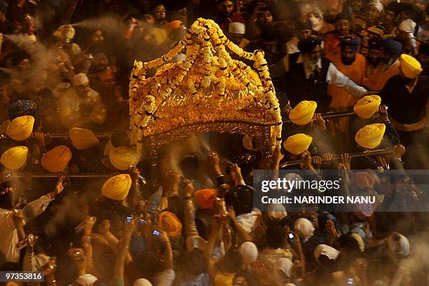 Indian Sikh devotees spray perfume on the Palki Sahib which carries The Guru Garnth Sahib in a procession from the Golden Temple to Sri Akal Takhat...