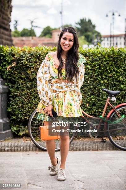 Wendy Nguyen, wearing a floral dress and orange bag, is seen during the 94th Pitti Immagine Uomo at Fortezza Da Basso on June 13, 2018 in Florence,...