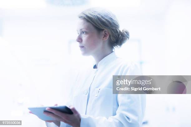 radiologist, holding digital tablet, looking away - sigrid gombert stock-fotos und bilder