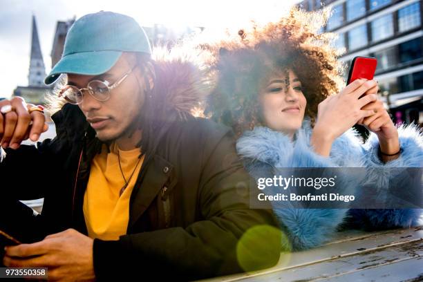 portrait of couple looking at smartphones - winter coat stock pictures, royalty-free photos & images