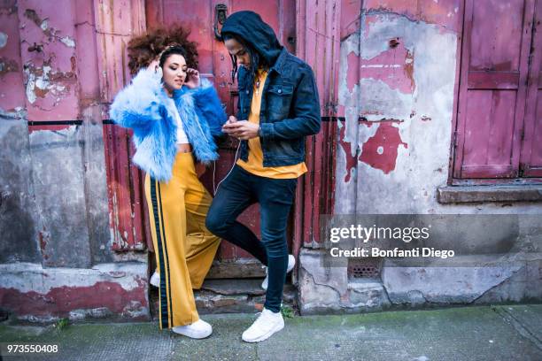 young couple listening to music through headphones on smartphone - youth culture music stock pictures, royalty-free photos & images