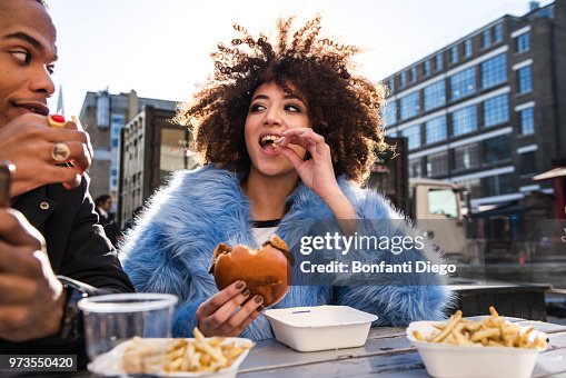 Young couple eating burger and chips outdoors Young couple eating burger and chips outdoors