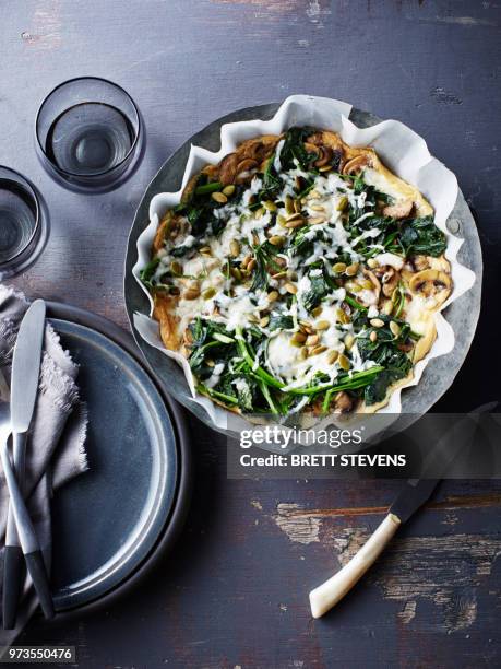 still life with bowl of spinach feta mushroom frittata, overhead view - frittata stock pictures, royalty-free photos & images