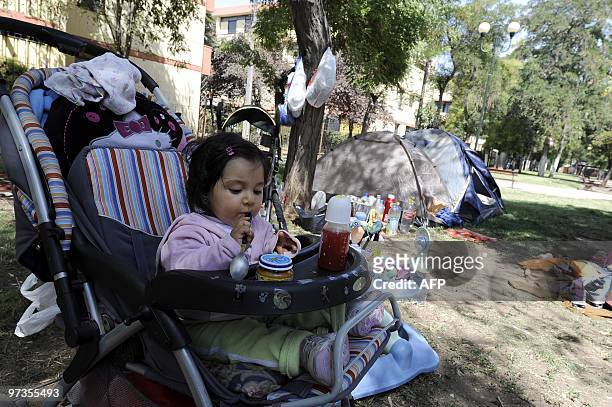 Little girl is seen ready to eat as her family camps in a park in Santiago on February 28 the day after a huge 8.8-magnitude earthquake rocked Chile...