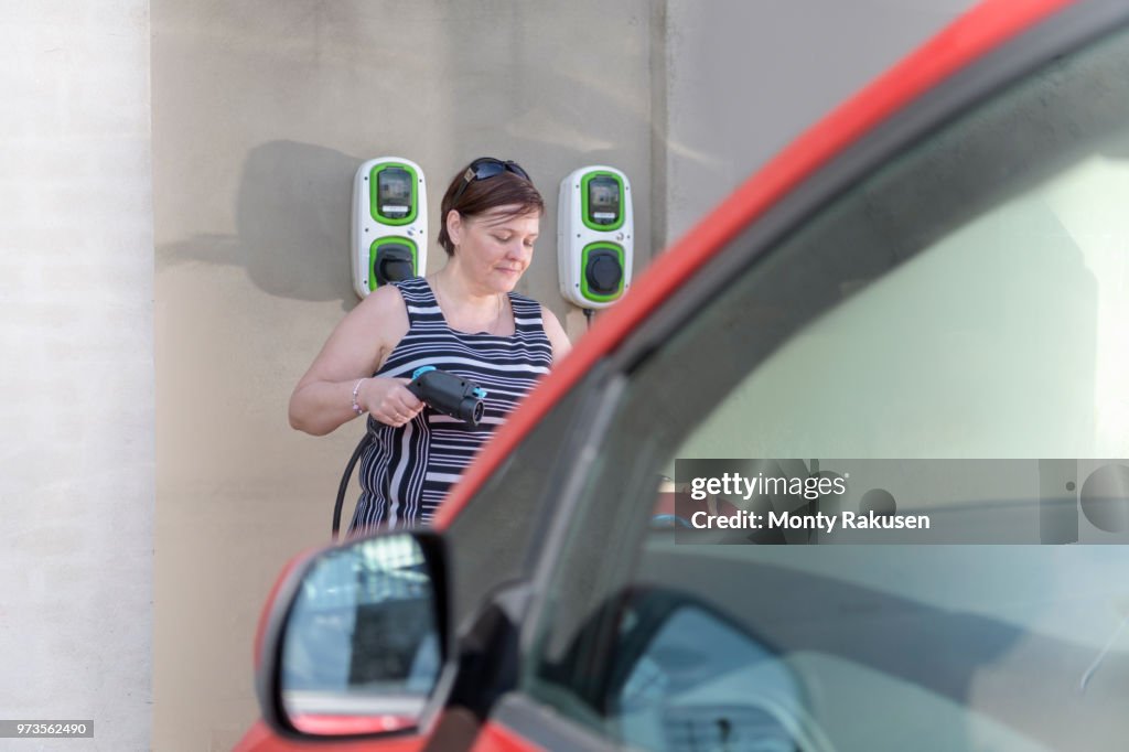 Woman charging electric car at city charging point