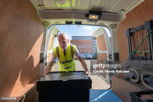 senior delivery driver loading all electric van - monty shadow stockfoto's en -beelden