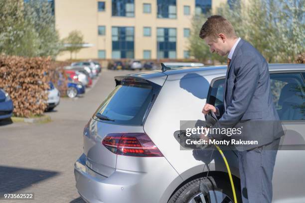 businessman charging electric car at charging point in business park - monty shadow - fotografias e filmes do acervo