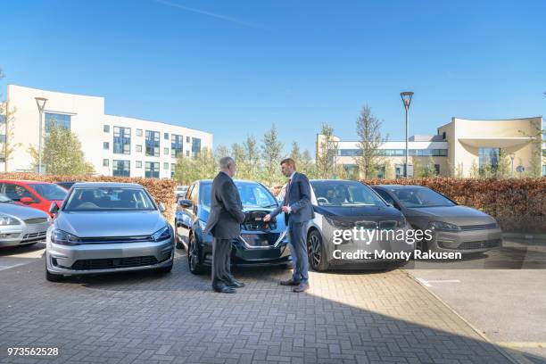 businessmen looking at range of electric cars in business park - monty shadow - fotografias e filmes do acervo