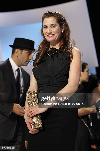 French actress Emmanuelle Devos stands on stage with her the award of the best supporting actress for her part in "A l'origine" during the 35th...