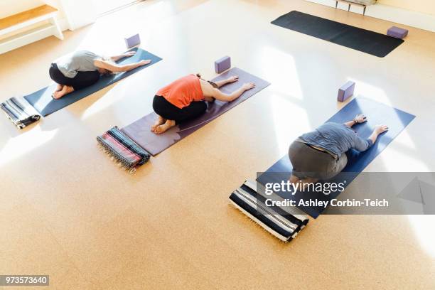 three women practicing balasana (child's pose) in yoga studio - teich stock pictures, royalty-free photos & images