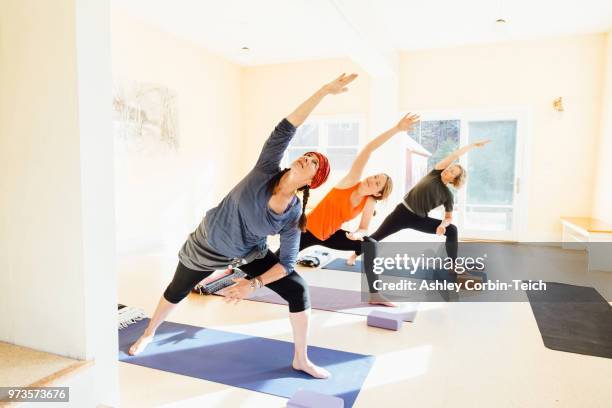 three women practicing extended side angle lunge, (parsvakonasana) yoga pose in yoga studio - teich stock pictures, royalty-free photos & images