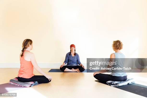 teacher and women practicing sukhasana yoga pose in yoga studio - teich stock pictures, royalty-free photos & images