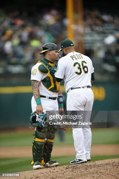 Bruce Maxwell and Yusmeiro Petit of the Oakland Athletics talk on the mound during the game against the Seattle Mariners at the Oakland Alameda...