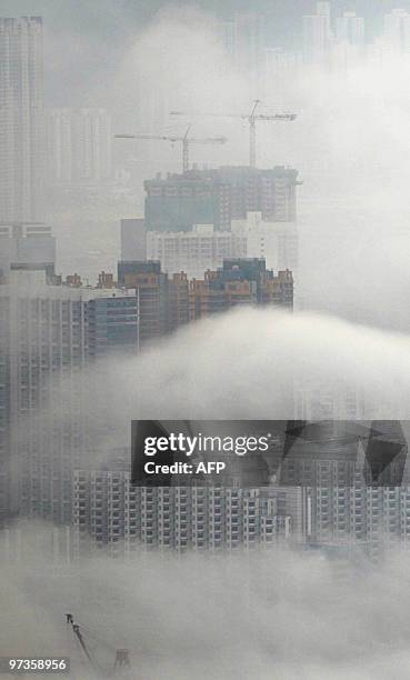 Thick cloud and fog shrouds buildings in the Kowloon area of Hong Kong on February 28, 2010. As heavy snow blizzards are affecting parts of mainland...