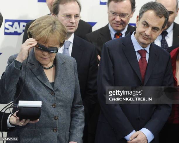 German Chancellor Angela Merkel inspects a "Head-Mounted Display" made by German software giant SAP next to Spanish Prime Minister Jose Luis...