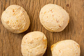 Pao de Queijo is a cheese bread ball from Brazil. Also known as Chipa, Pandebono and Pan de Yuca. Group of snacks on rustic wood, flat lay design.