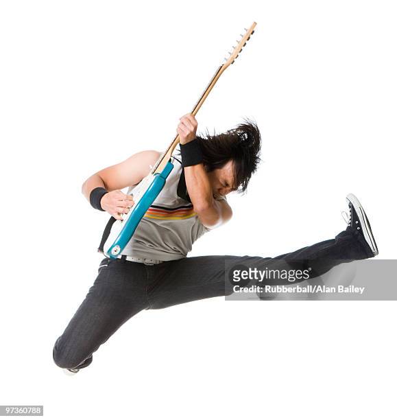 young man jumping and playing guitar, studio shot - spagat stock-fotos und bilder