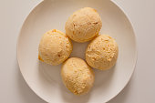 Pao de Queijo is a cheese bread ball from Brazil. Also known as Chipa, Pandebono and Pan de Yuca. Snacks over white plate, minimalism.